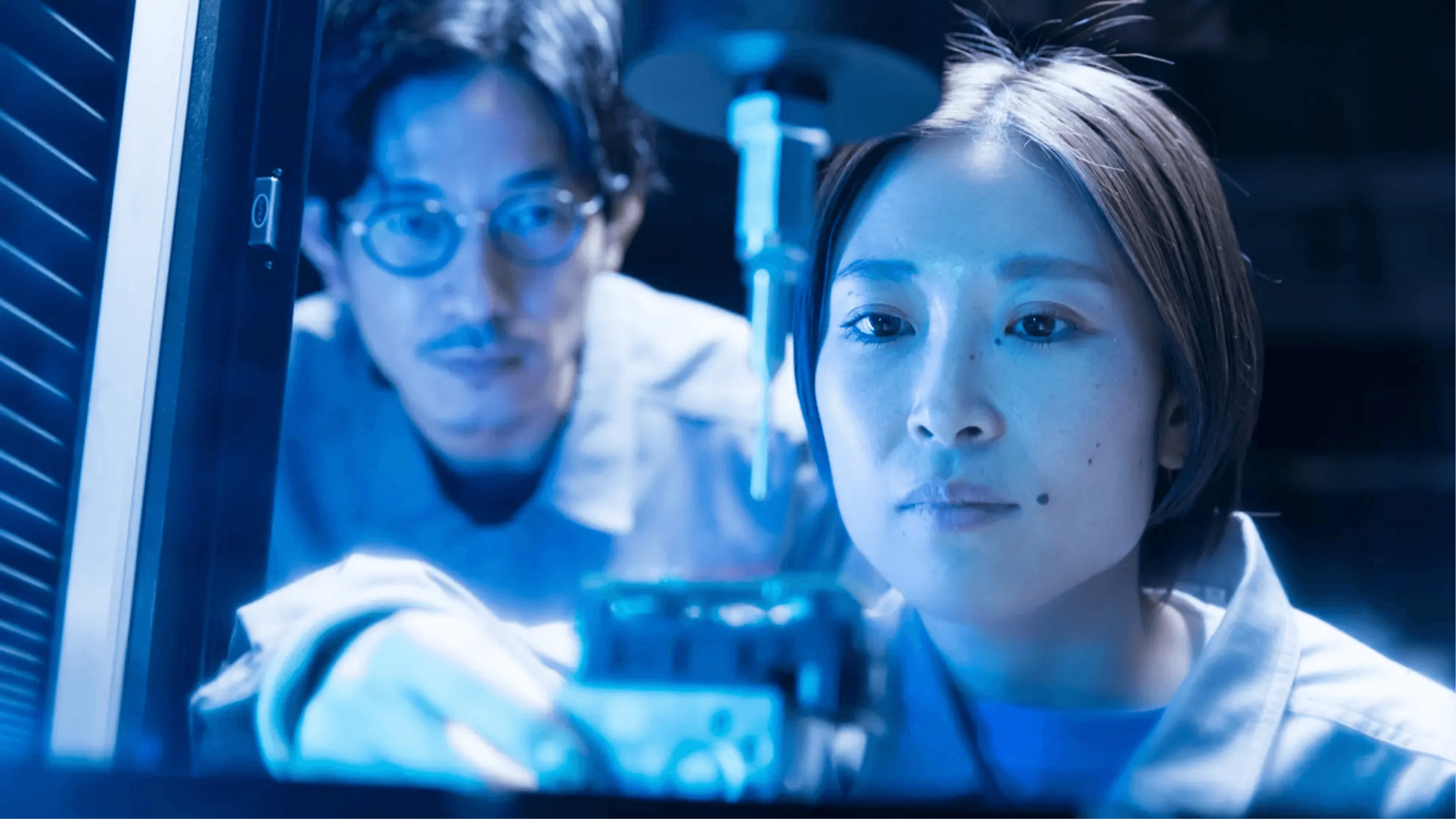 Zwei Wissenschaftler arbeiten in einem modernen Labor mit blauem Licht und digitaler Ausrüstung und konzentrieren sich auf ihre Forschung.