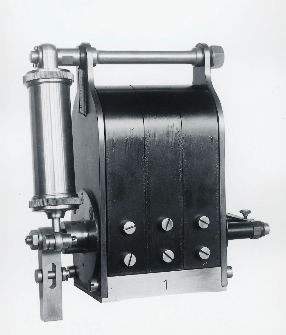 Historische Schwarz-Weiß-Aufnahme des ersten Bosch-Magnetzünders von 1887 vor neutralem Hintergrund.